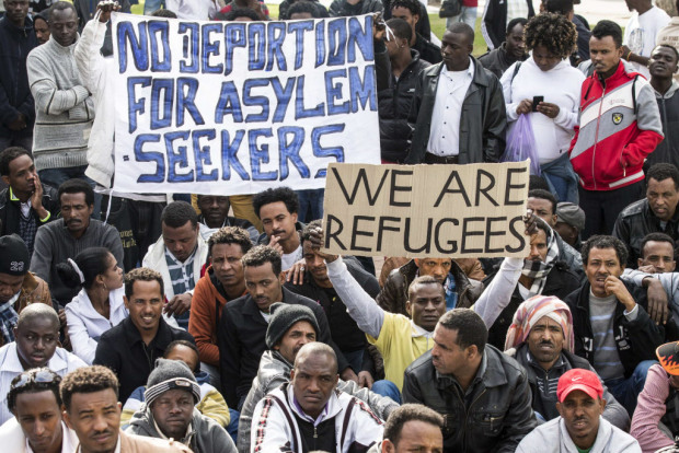 Protestors hold up signs in English as thousands of African asylum seekers who entered Israel illegally via Egypt staged a protest in Tel Aviv on January 7, 2014, slamming the Jewish state's long-term detention of illegal immigrants. The migrants, primarily from Eritrea and Sudan, are protesting for the third day in a row to call for help in the face of Israel's refusal to grant them refugee status and its detention without trial of hundreds of asylum seekers. AFP PHOTO / JACK GUEZJACK GUEZ/AFP/Getty Images