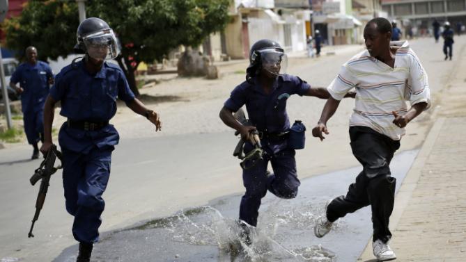 Riot police chase a demonstrator in Bujumbura, Burundi, Monday, May 4, 2015. Anti-government demonstrations resumed in Burundi's capital after a weekend pause as thousands continue to protest the president's decision to seek a third term. (AP Photo/Jerome Delay)