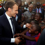 French President Emmanuel Macron greets children as he arrives to visit a school in Ouagadougou