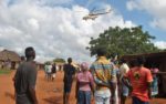 Residents look at a police helicopter patrolling near the closed house, where Italian volunteer for the Italian charity Africa Milele lived before she was seized, in Chakama trading centre of Magarini, Kilifi County